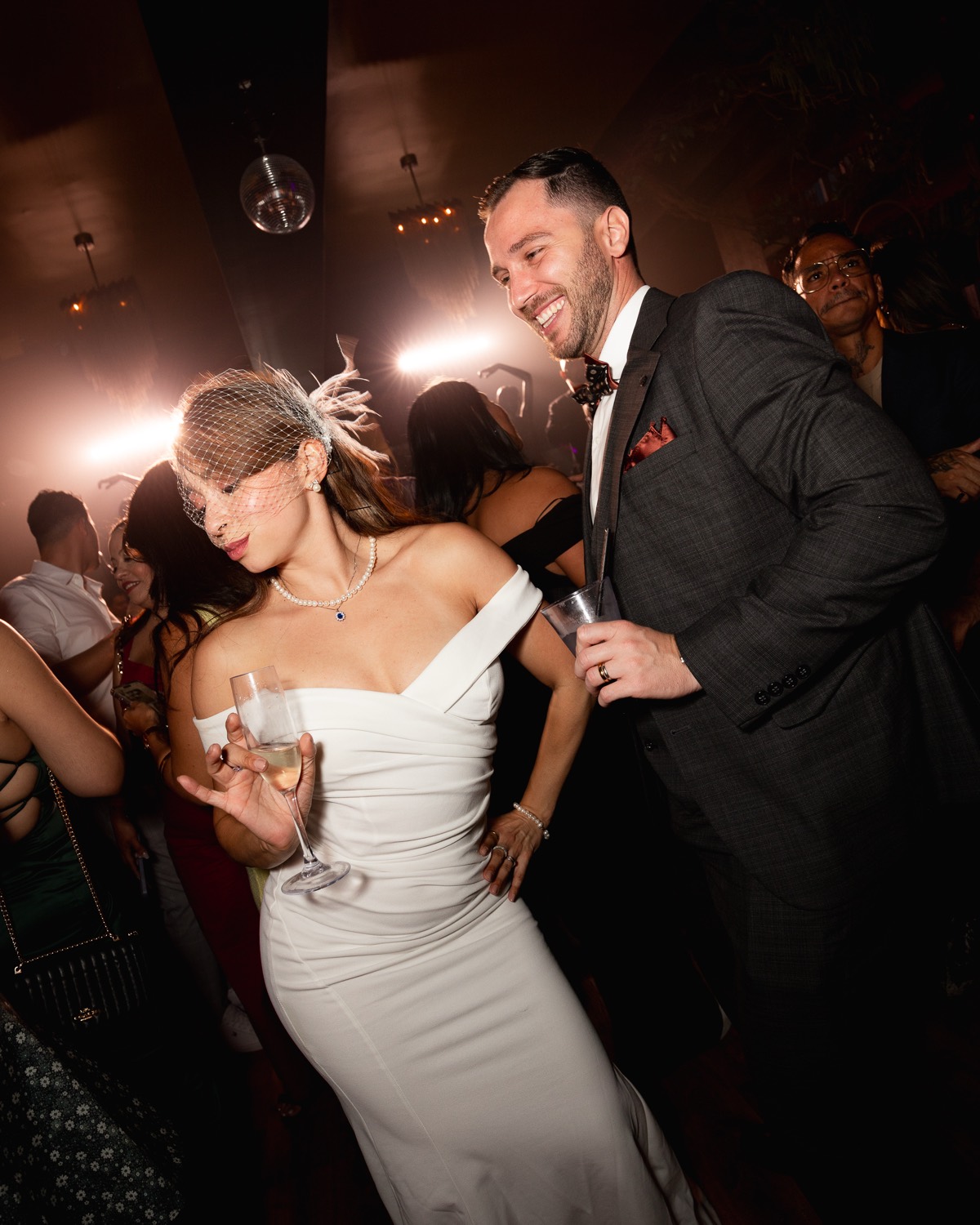 The bride and the groom share a glass of champagne on the dancefloor