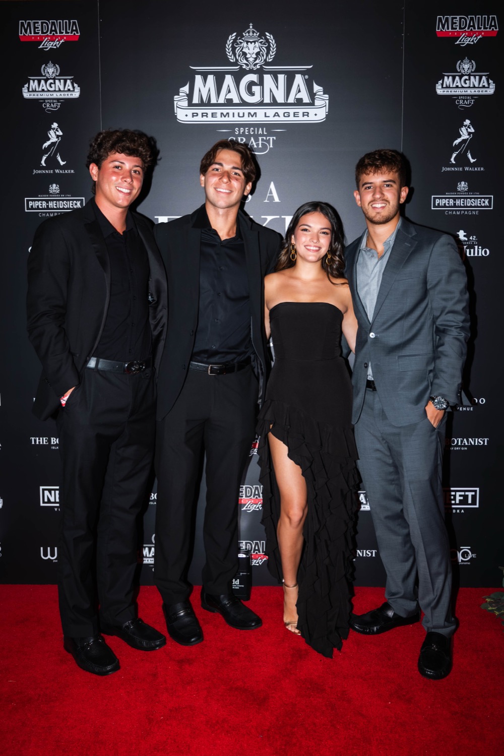 Glamorous guests on the red carpet at the It's a Fake Wedding step-and-repeat, in front of the sponsor wall